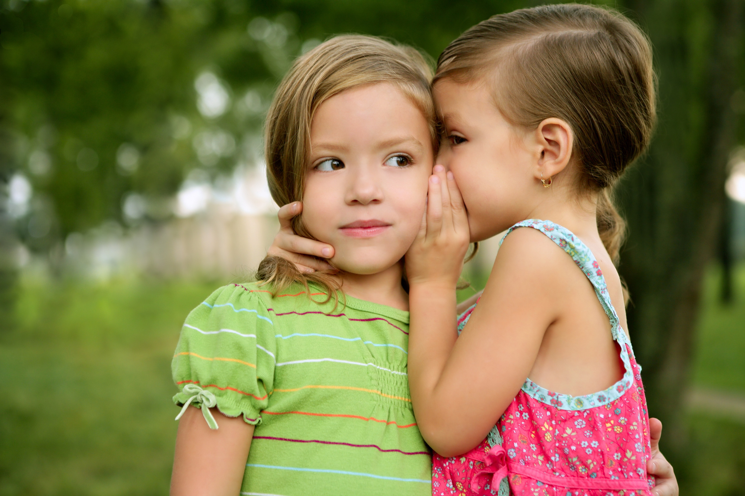 Two twin little sister girls whisper in ear Two twin little sister girls whisper in ear