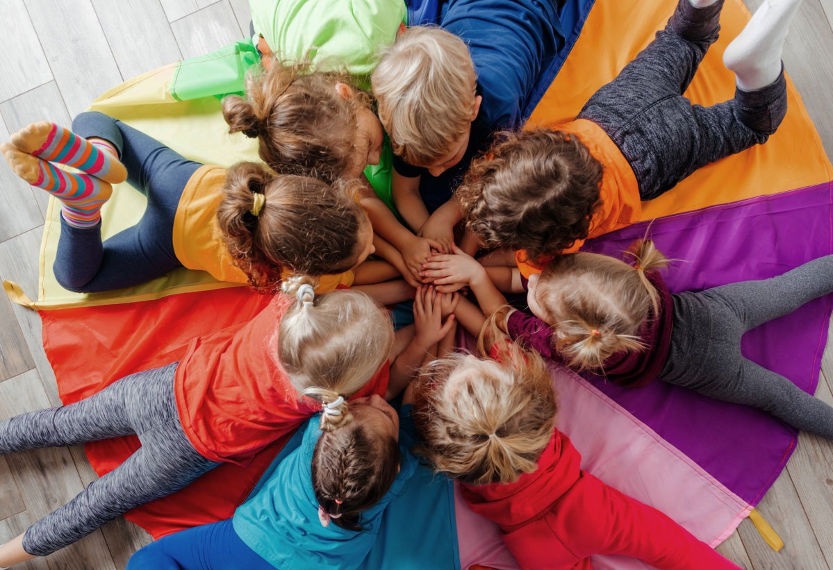 Cheerful children playing team building games on a floor