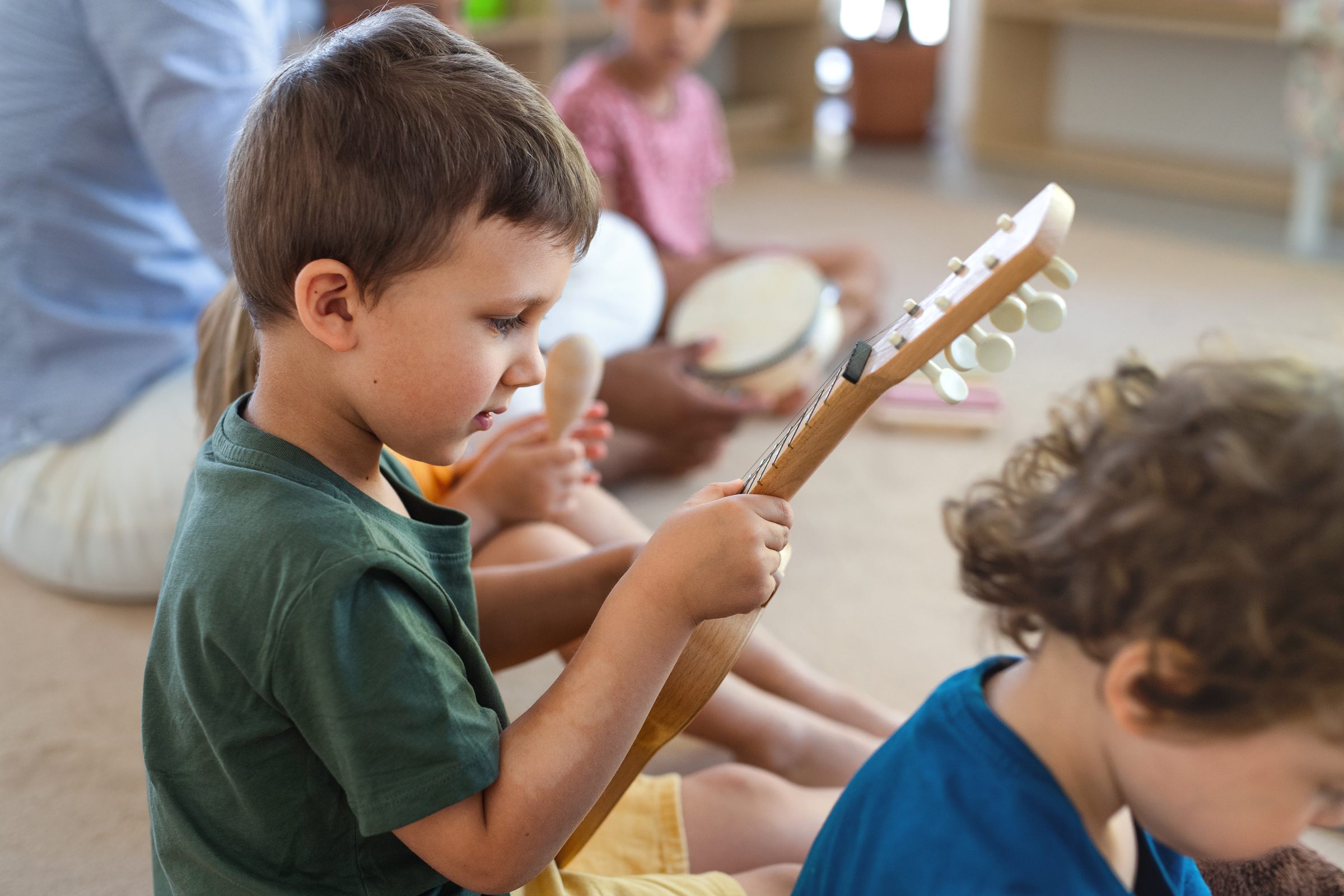 Group of small nursery school children sitting on floor indoors in classroom, playing musical instruments. Group of small nursery school children sitting on floor indoors in classroom, playing musical instruments.