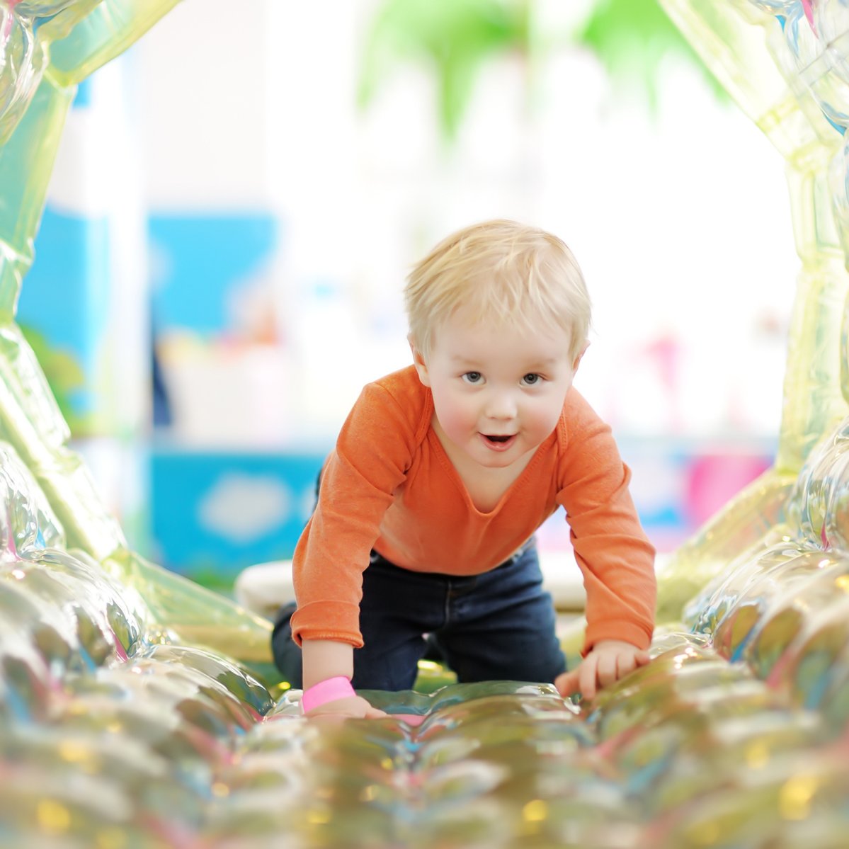 Active toddler boy having fun on inflatable attraction in entertaining center. Funny child is playing on indoor playground. Kids amusement park.